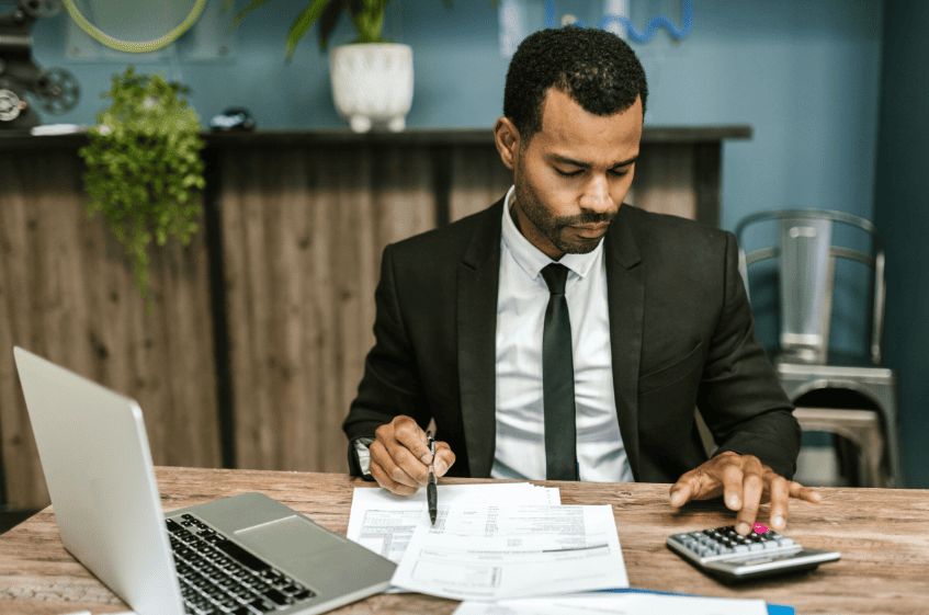 Contador realizando cálculos com planilhas e calculadora