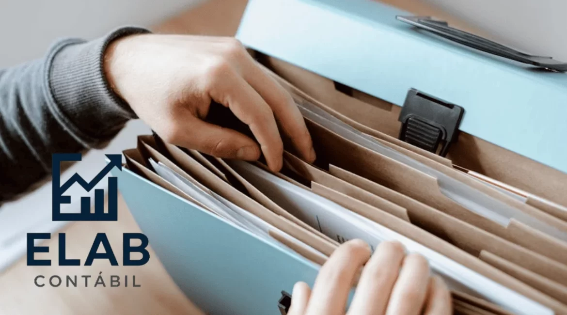 Mão organizando arquivos e documentos para controlar as finanças