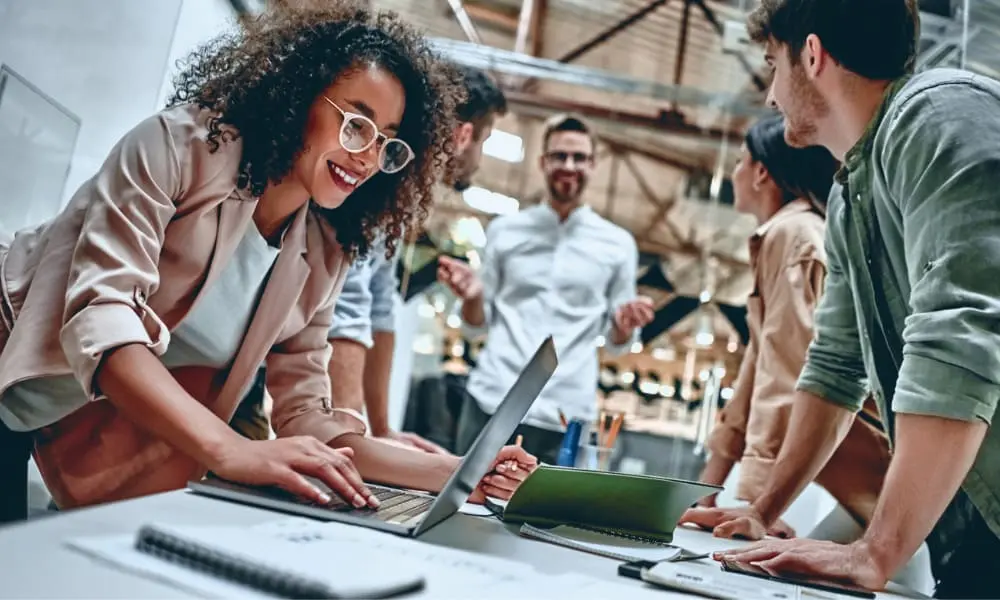 Funcionários felizes e motivados trabalhando juntos em ambiente corporativo.