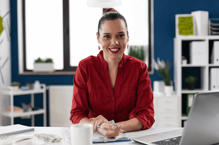 Secretária corporativa sorrindo enquanto trabalha no escritório.