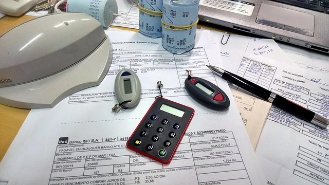 Imagem de documentos, calculadora, caneta e tokens de conta bancária sobre uma mesa, representando organização financeira empresarial para pagar menos impostos